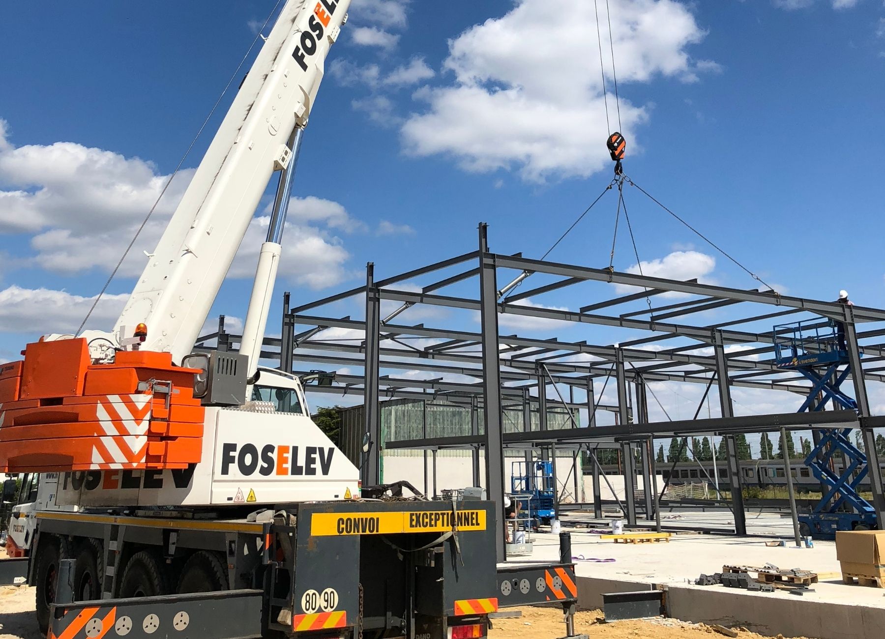 Pose d’un élément de toiture métallique à l’aide d’une grue sur structure en acier.