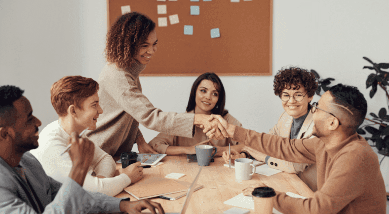 Team meeting with colleagues shaking hands, representing data-driven collaboration for demand planning