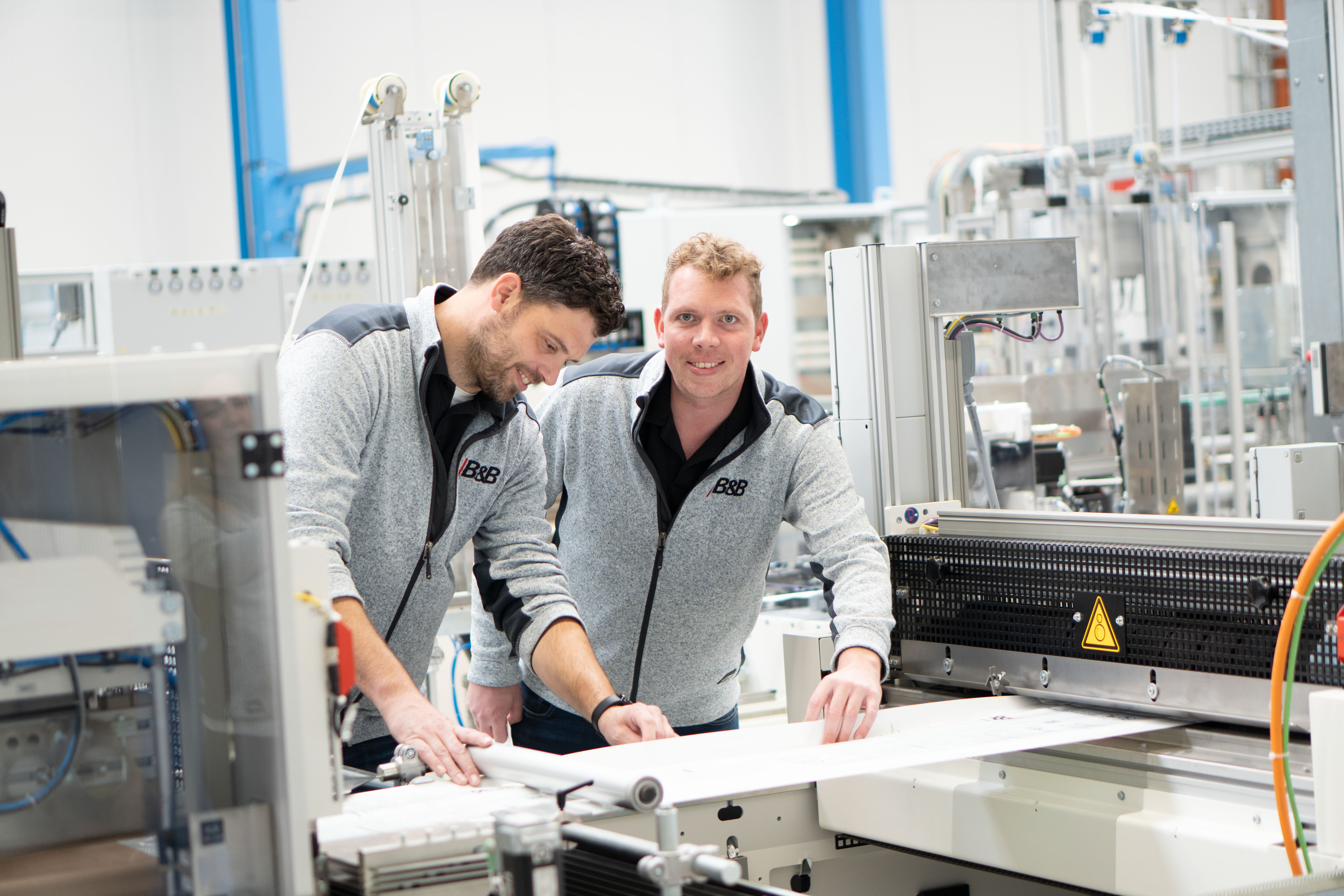 Two happy workers in a factory. Skilled workers at work in manufacturing.