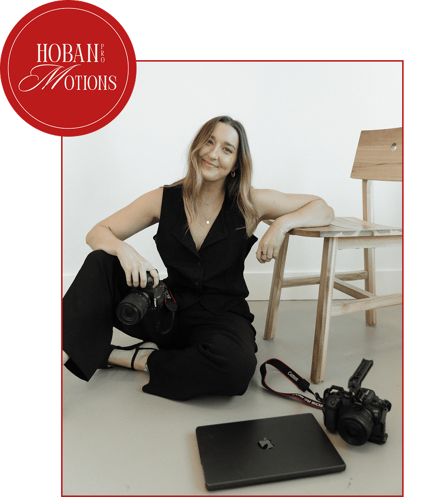 Female videographer sitting with laptop and cameras in a studio
