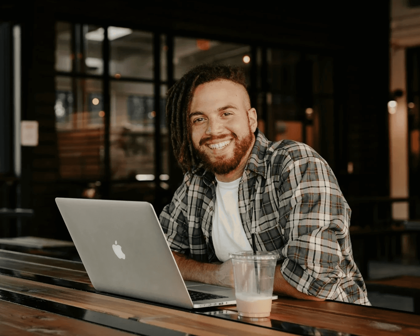 Smiling man working on laptop at a café, representing balance and productivity in daily life