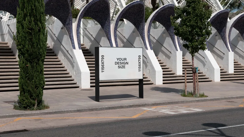 Street-level billboard with a blank white display set against a backdrop of modern architectural stairs featuring curved, mosaic-tiled arches. A tree and roadside elements frame the urban setting.