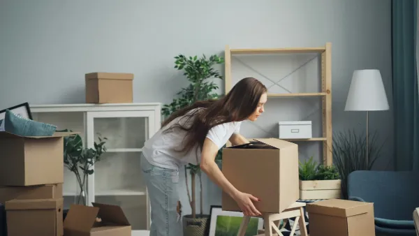 Joven desempaquetando cajas durante la mudanza a su nuevo piso. Seguro de inquilinos Allianz para asegurar tus muebles y responsabilidad civil.