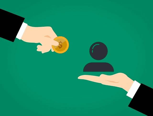 One hand is holding a coin and the other hand is holding an emoji of a person and they are giving it to each other