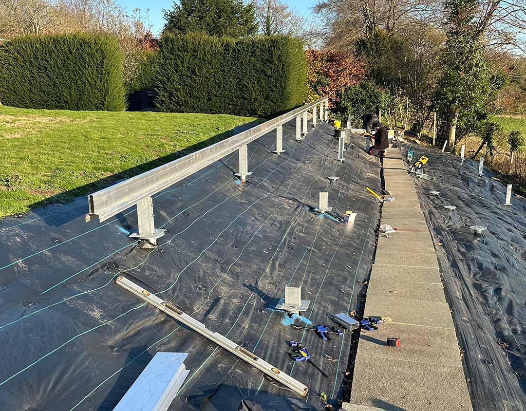 Ground screw foundation system installed on a hillside without concrete for a large residential solar project in Puttenham.