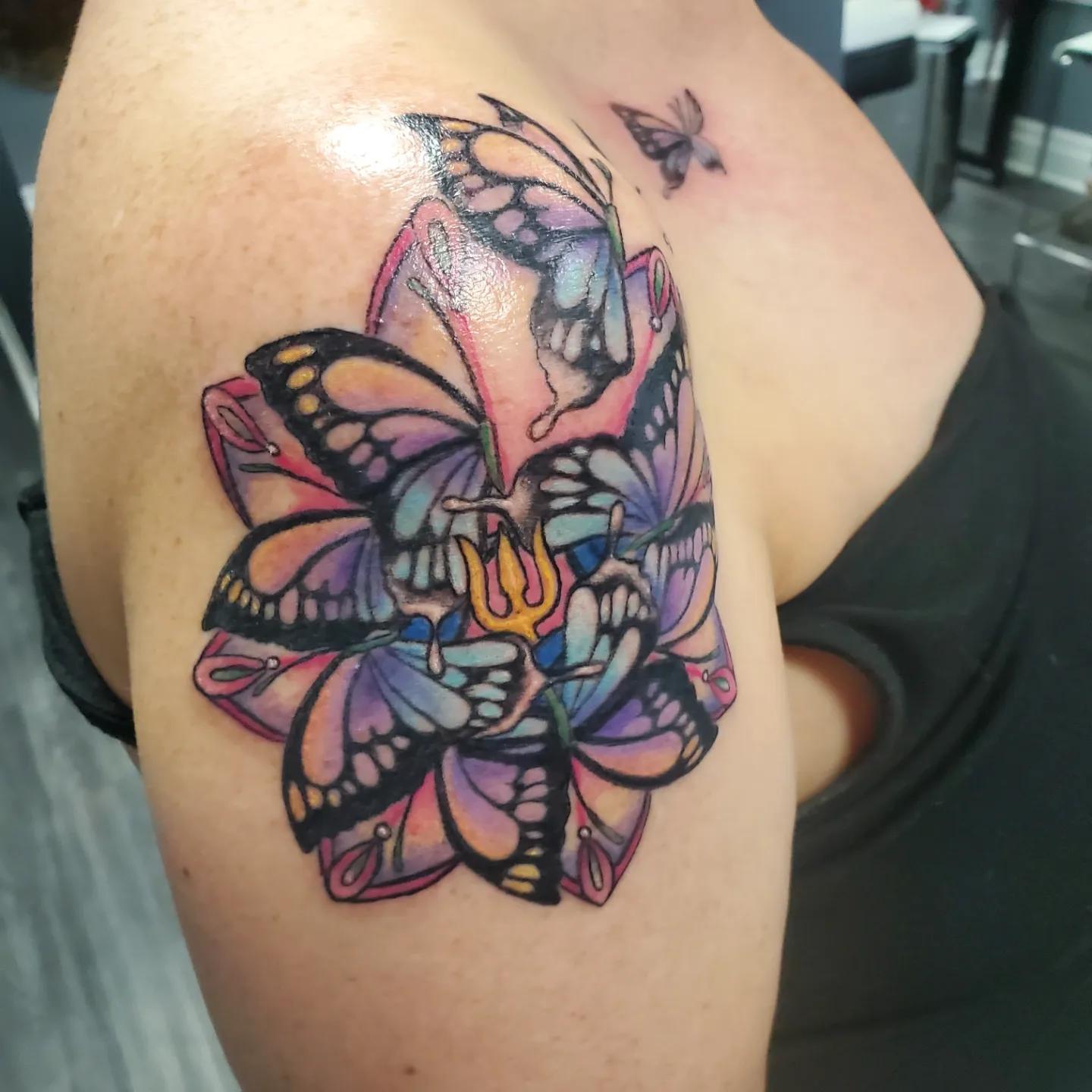 Colour butterfly and orchid tattoo on an upper arm