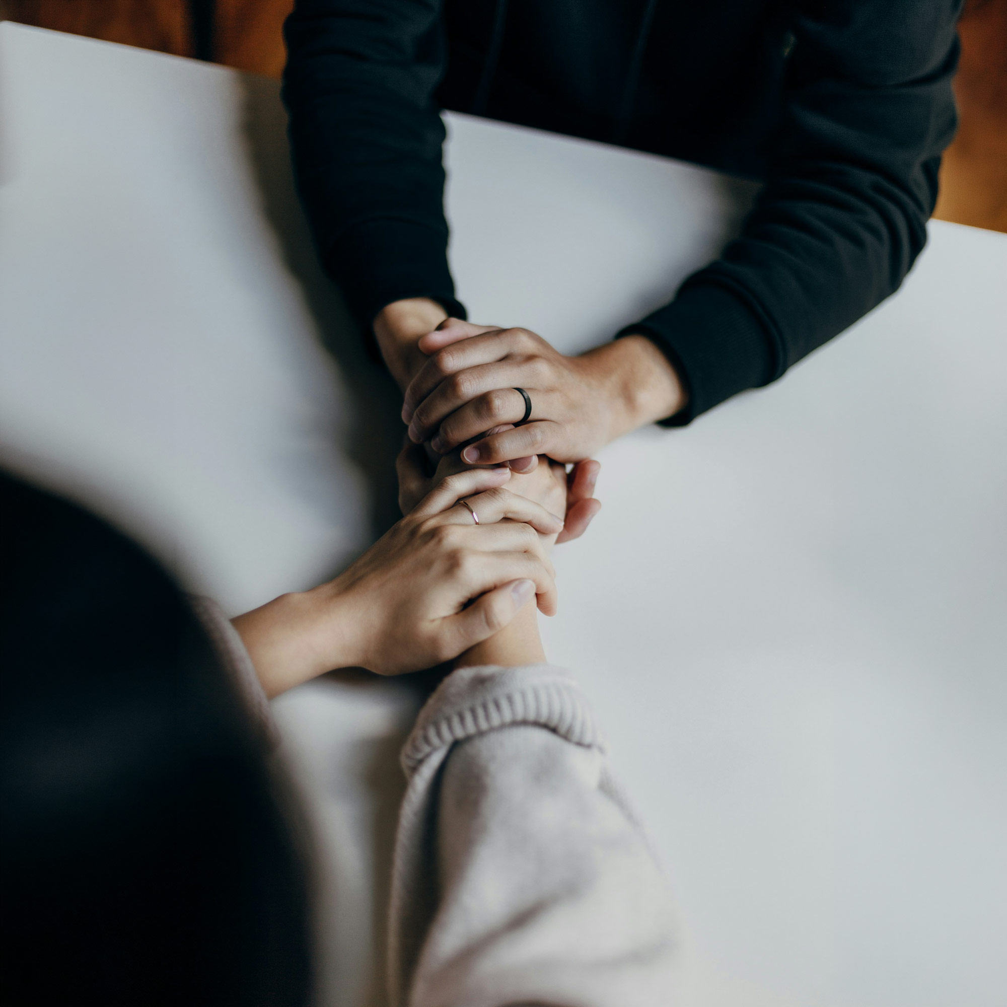 Zwei Personen halten sich gegenseitig die Hände in einer unterstützenden Geste, Nahaufnahme