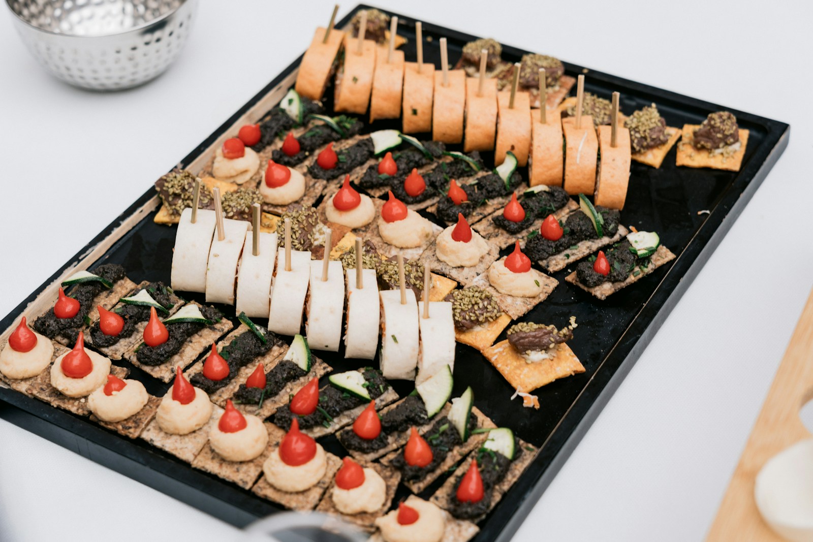 Sortiment von Fingerfood-Häppchen auf einem schwarzen Tablett