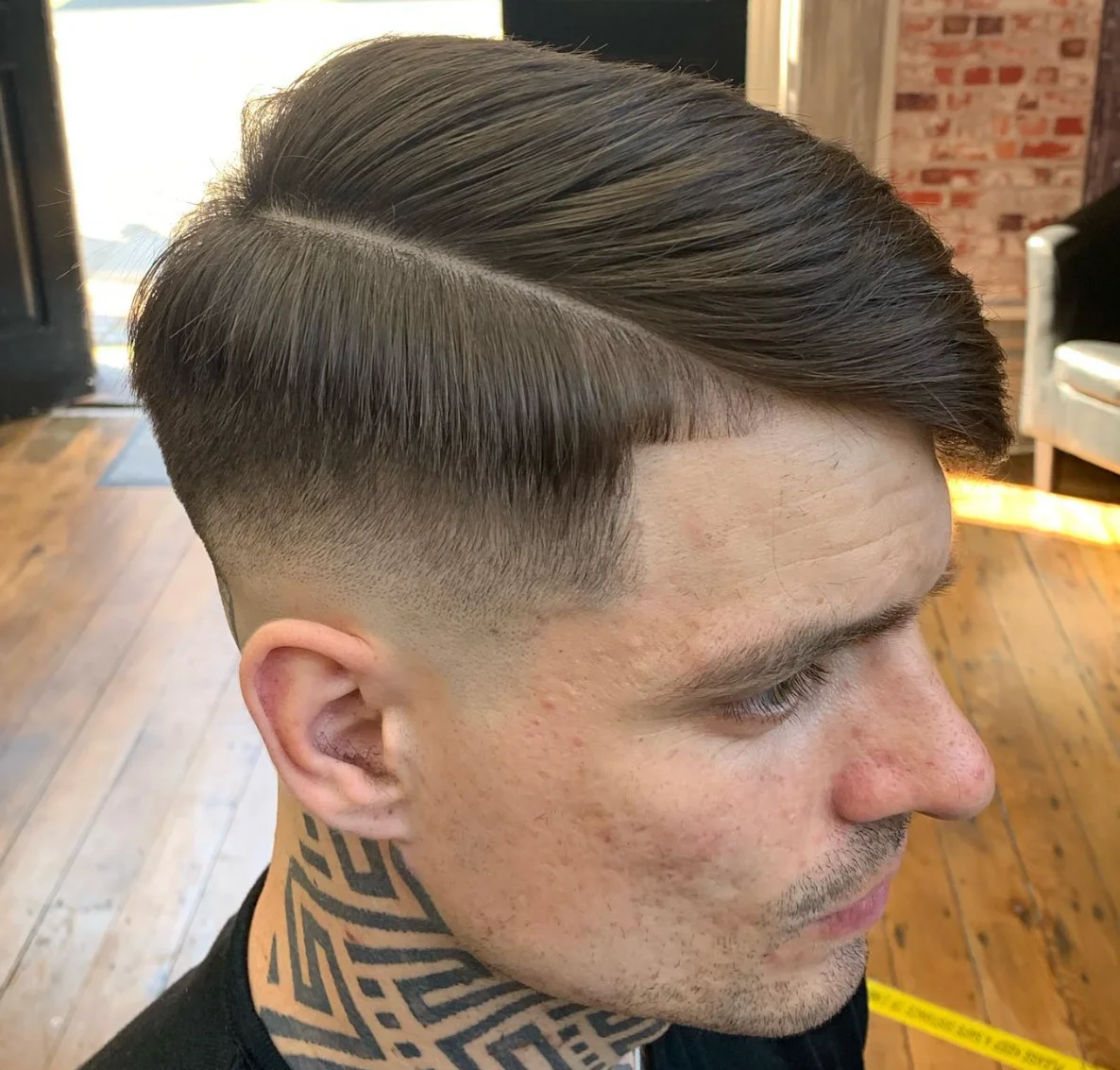 Older man with a precisely styled haircut, seated in a premium barbershop setting.