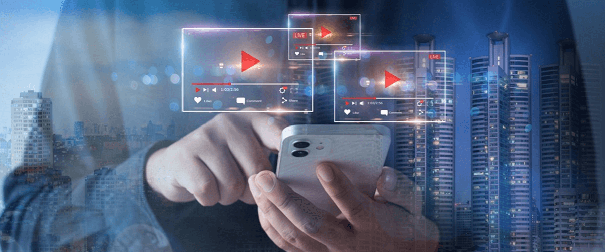 A person using their phone with multiple video player icons floating over a city landscape, representing how professional videos improve engagement across marketing channels.