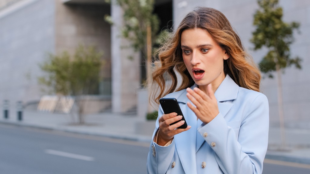 Woman looking at phone shocked by missed message