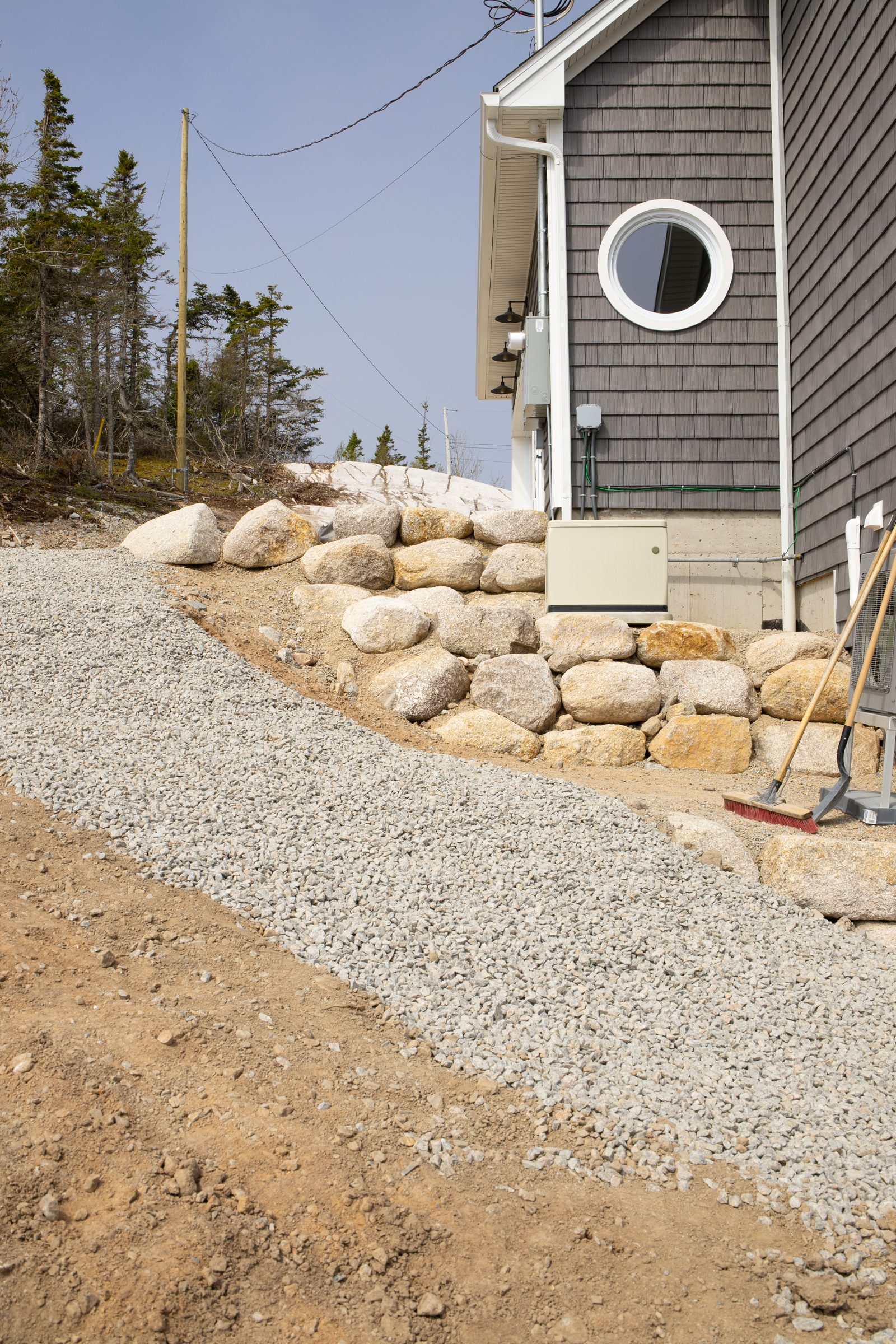 Armour stone wall with drainage gravel behind it next to a house