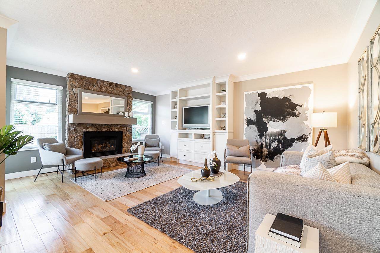 Modern living room with large windows, a fireplace, comfortable seating, and a neutral color palette.