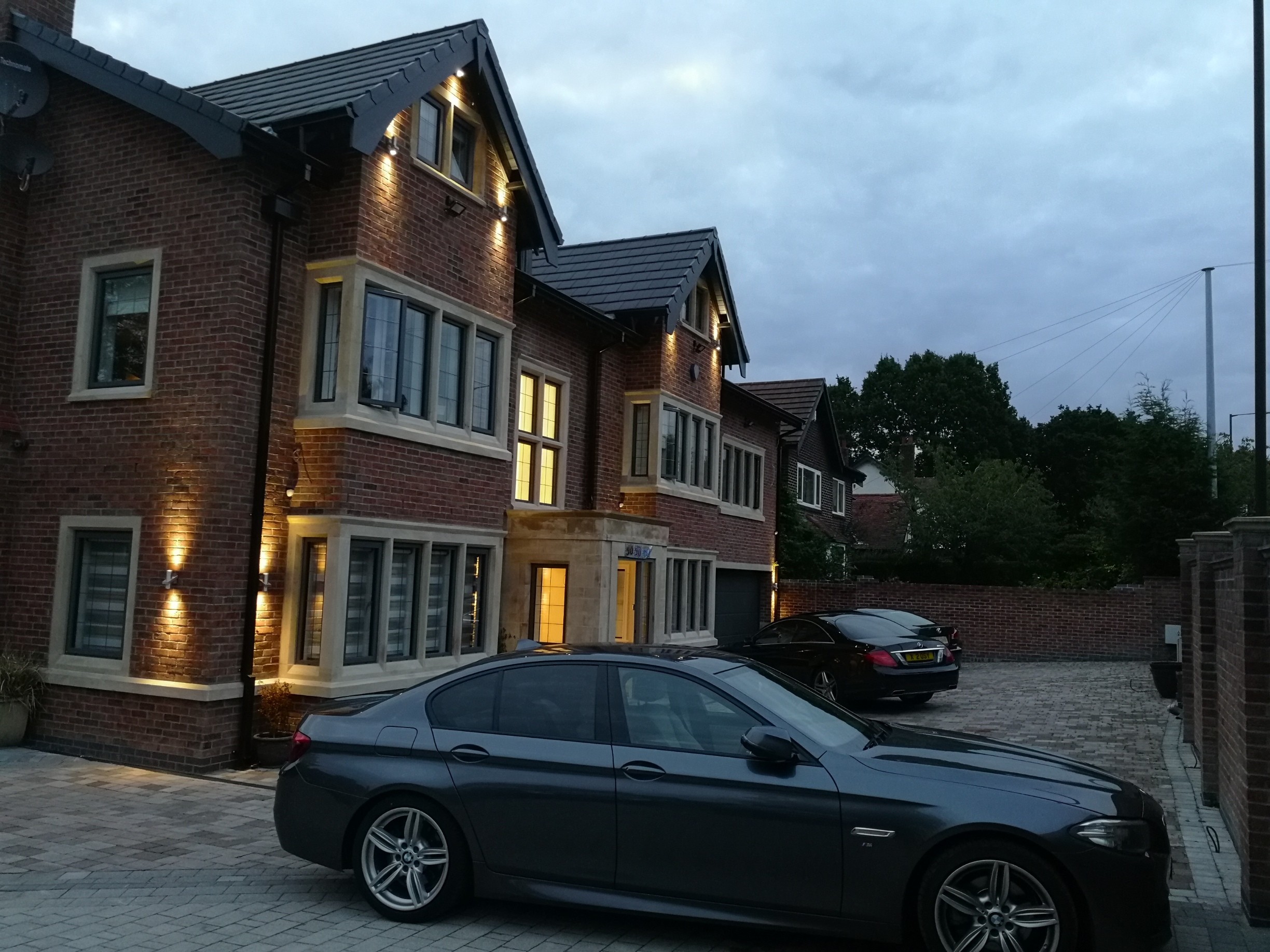 Luxury six-bedroom house remodel in Bramhall, Cheshire, featuring bespoke stonework, bay windows, and evening architectural lighting.
