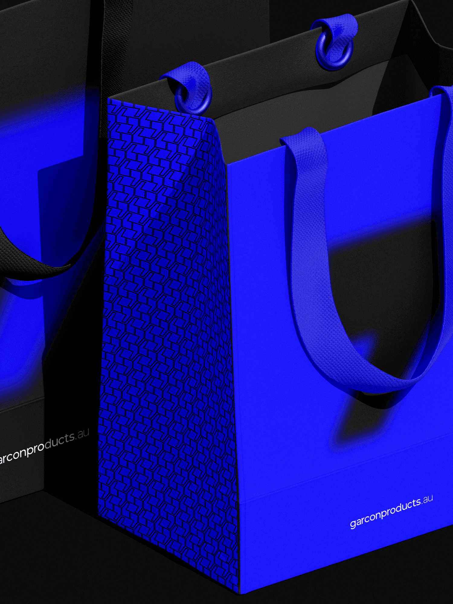 Person wearing black clothing carrying a black tote bag with a green globe-like geometric symbol, standing against a concrete wall in sunlight and shadow.