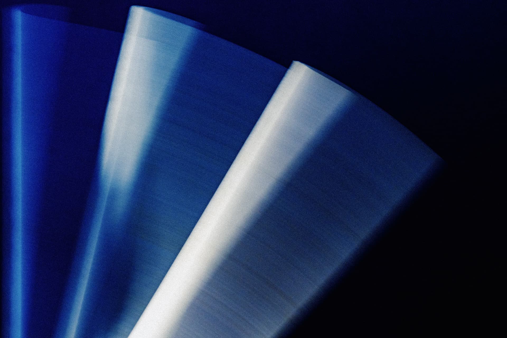 Long exposure photograph of HB pencils in motion, multiple angular surfaces converging, slow shutter speed creating blue-toned facets in geometric composition with graduated light