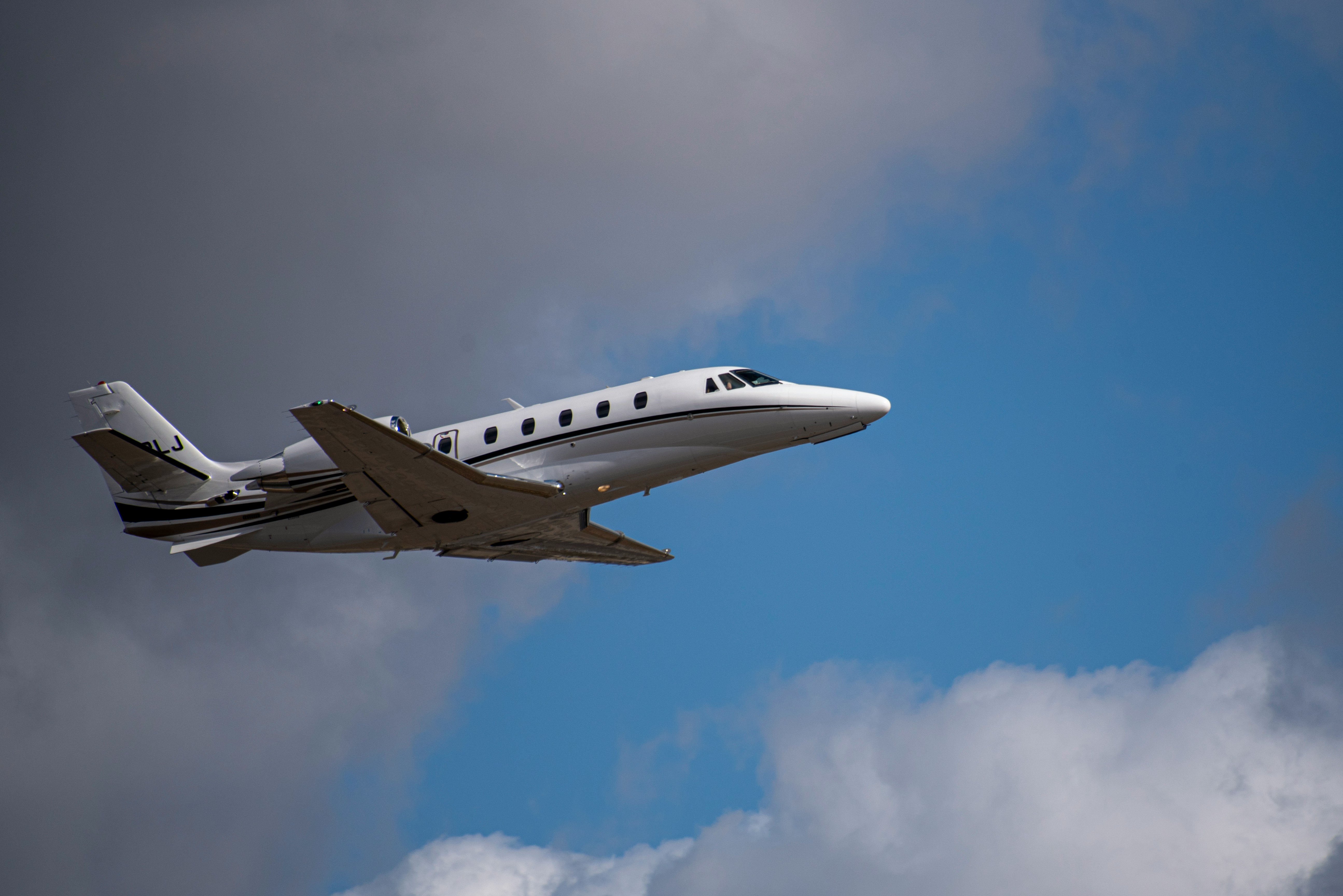 a small plane flying through a cloudy blue sky