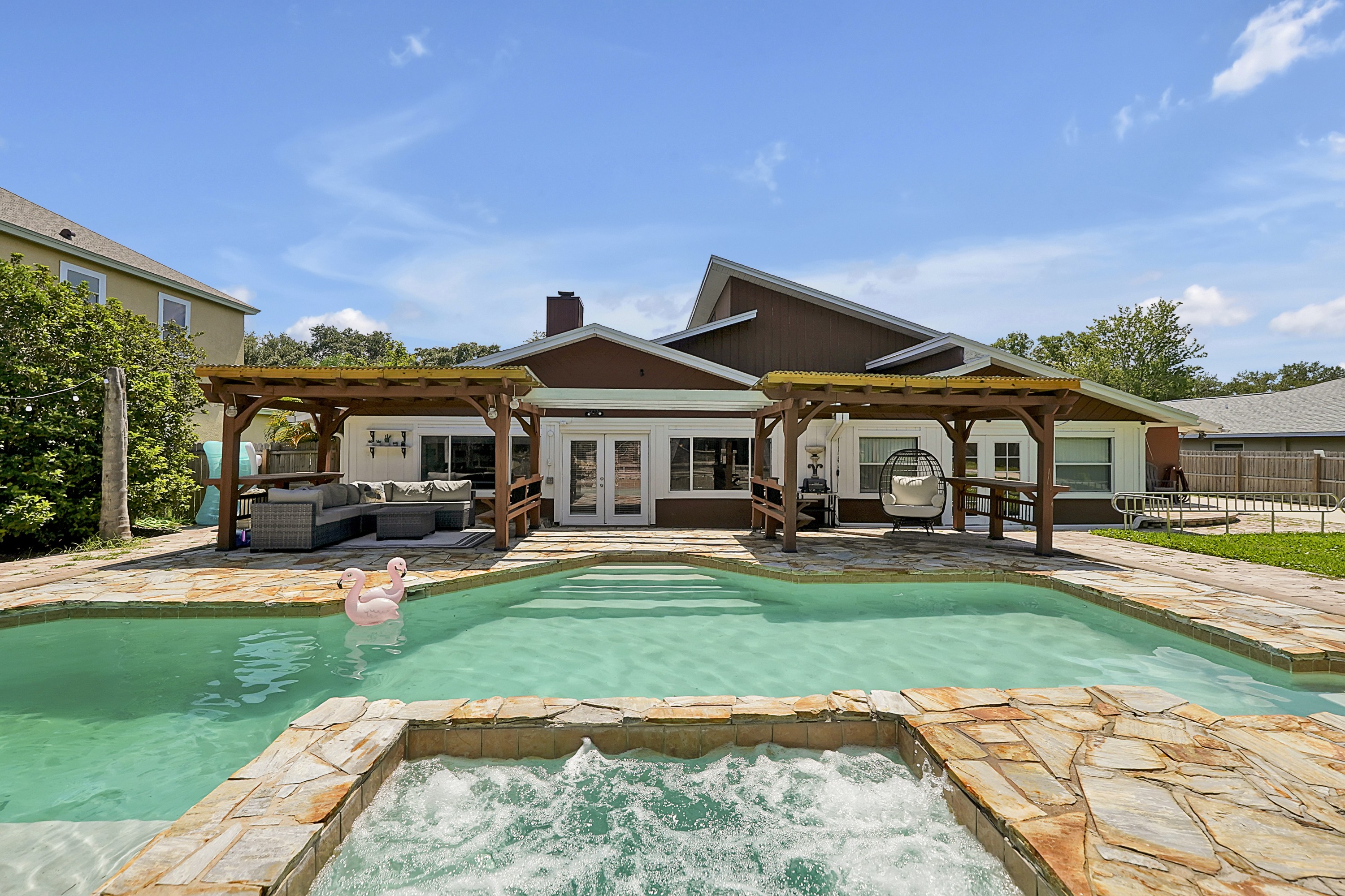 Private vacation rental pool and spa with covered outdoor seating behind the home.