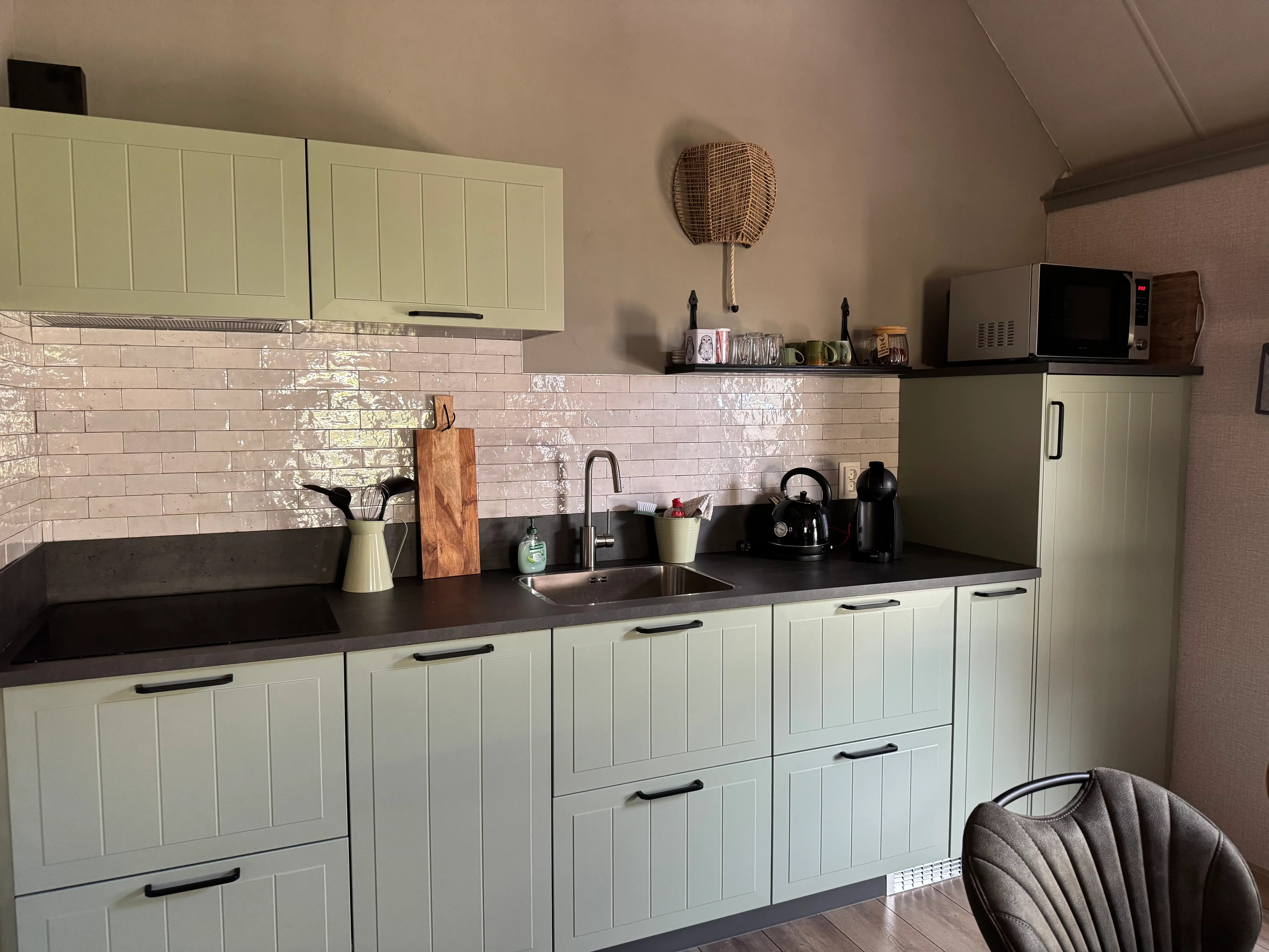 Moderne groene keuken met inductiekookplaat en kookvoorziengen.