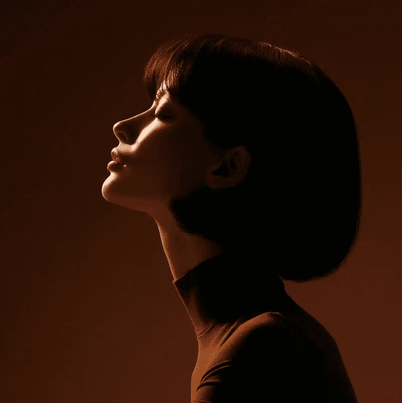 Side profile of a woman in soft dramatic lighting with warm tones.