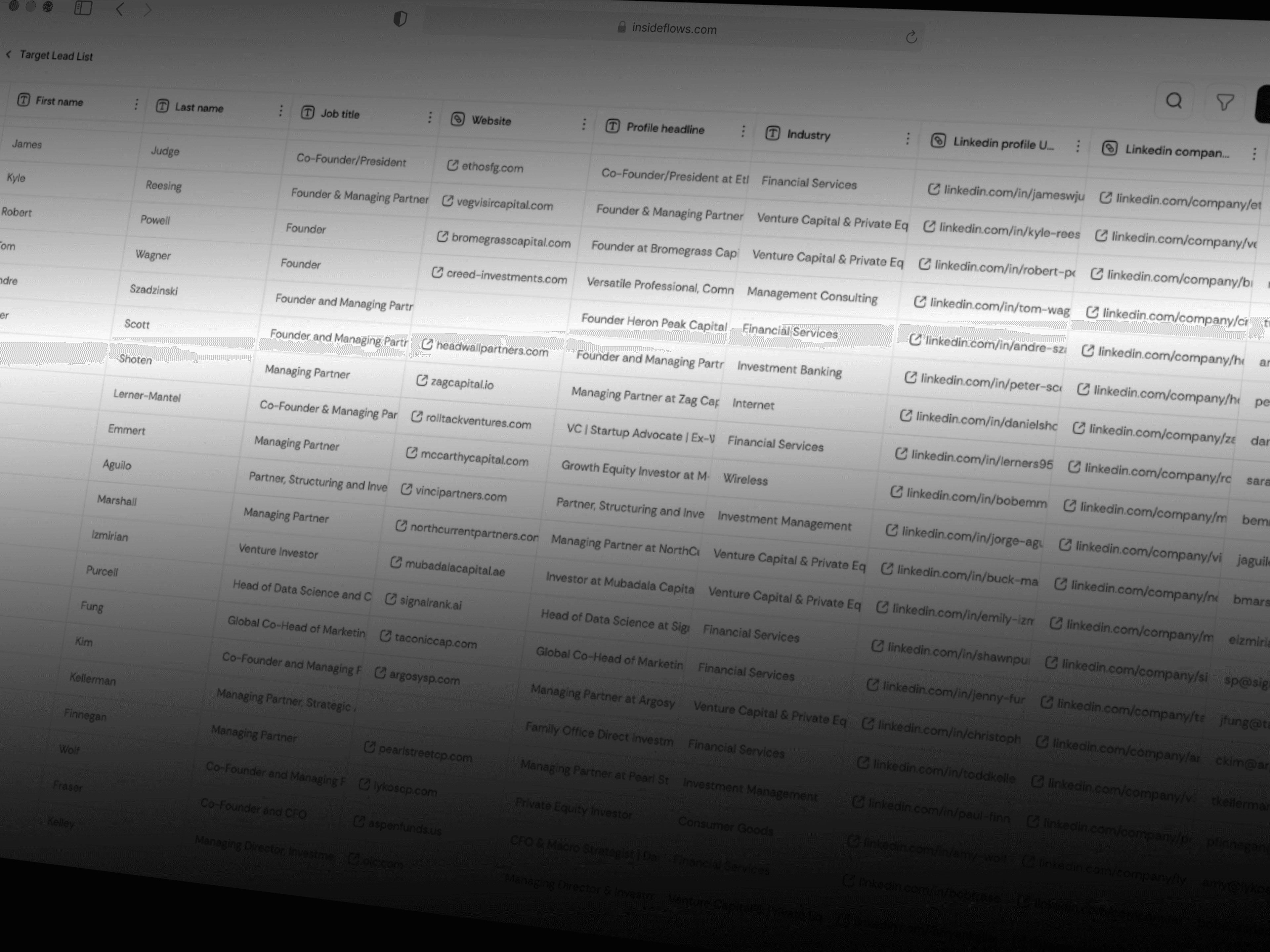 Man with glasses and tied-back hair writing at a desk while looking at a tablet.