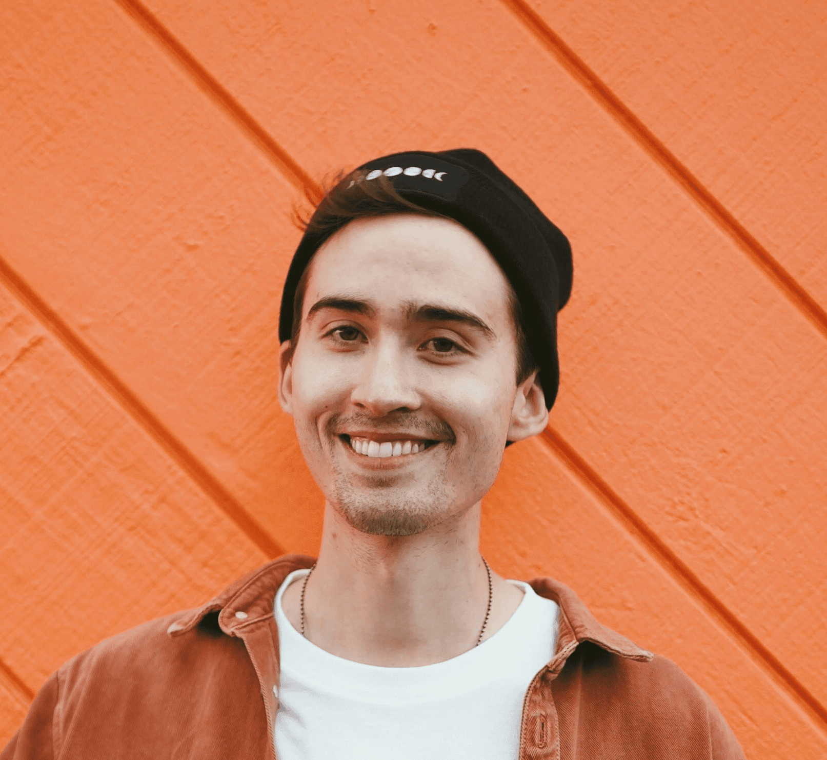 man in brown leather jacket standing beside red wall