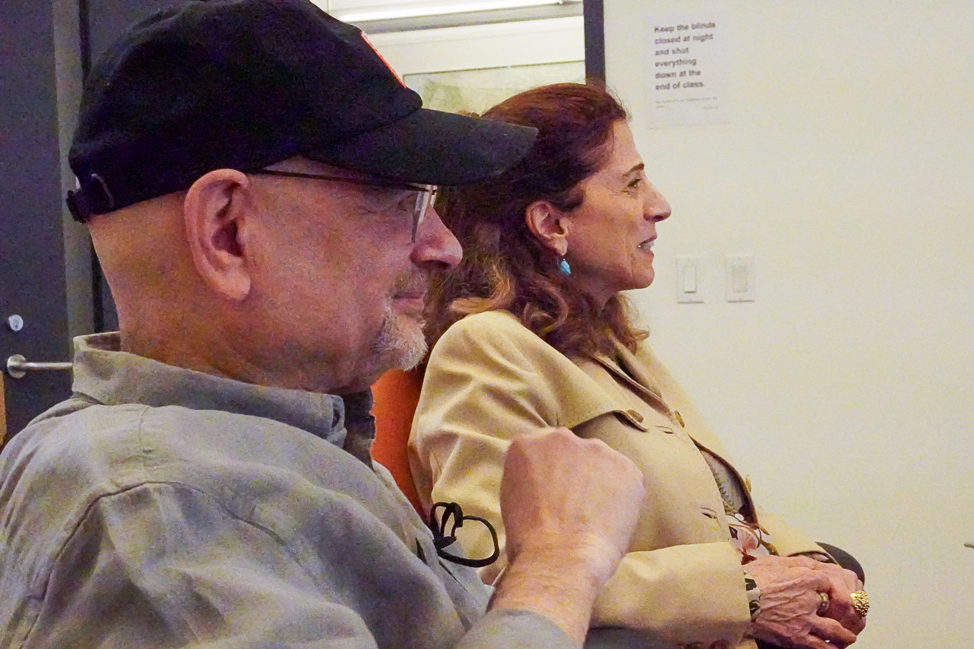 A photo of a man and a woman looking at something while sitting in a room.