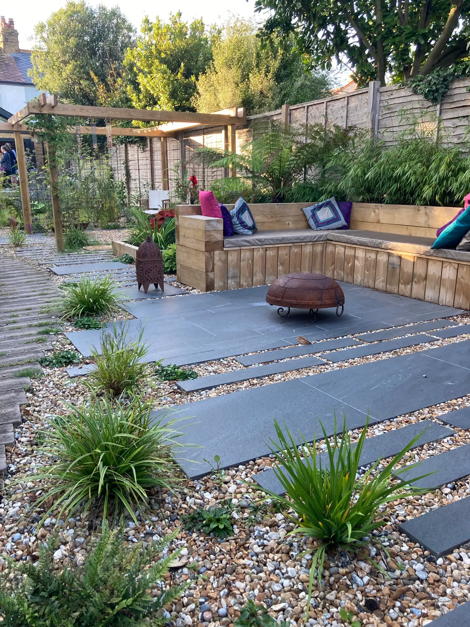 A landscaped garden features stone paths, greenery, and seating areas, creating a tranquil outdoor space.