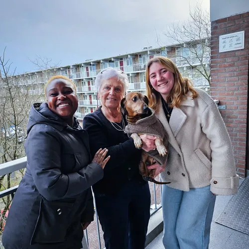 Twee VoorUiters met een buurtbewoner en haar hond op de galerij