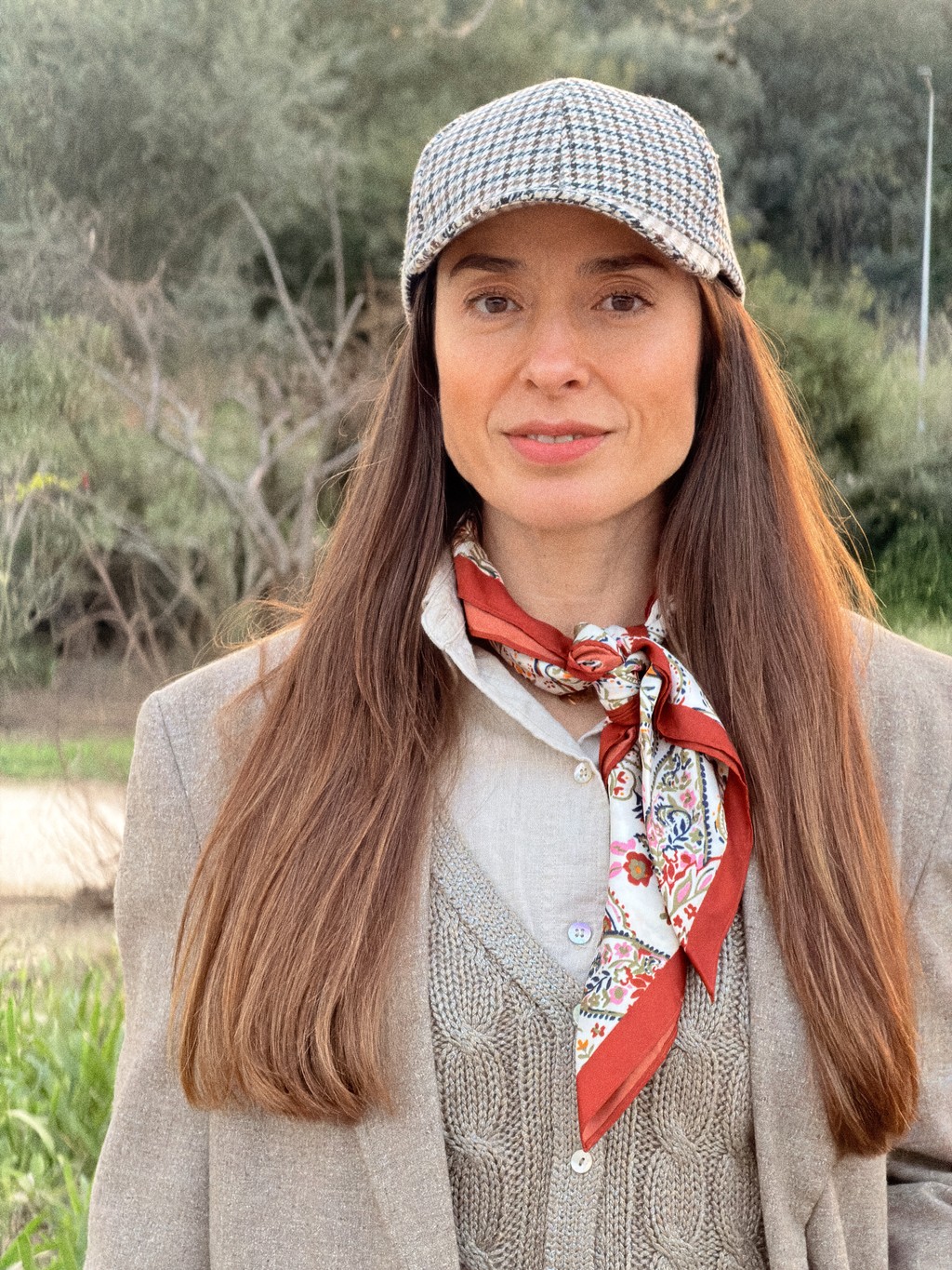 A smiling man with short hair stands with arms crossed, wearing a dark shirt against a neutral background.