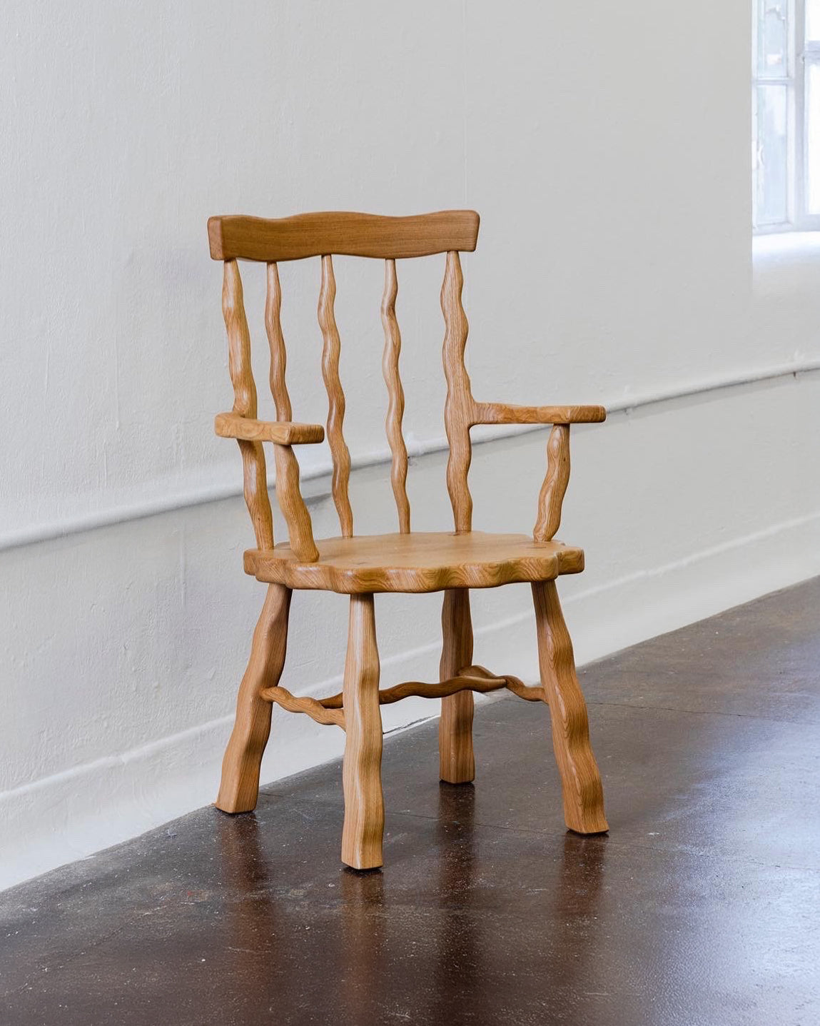 Oak Windsor armchair on a grey floor with white walls
