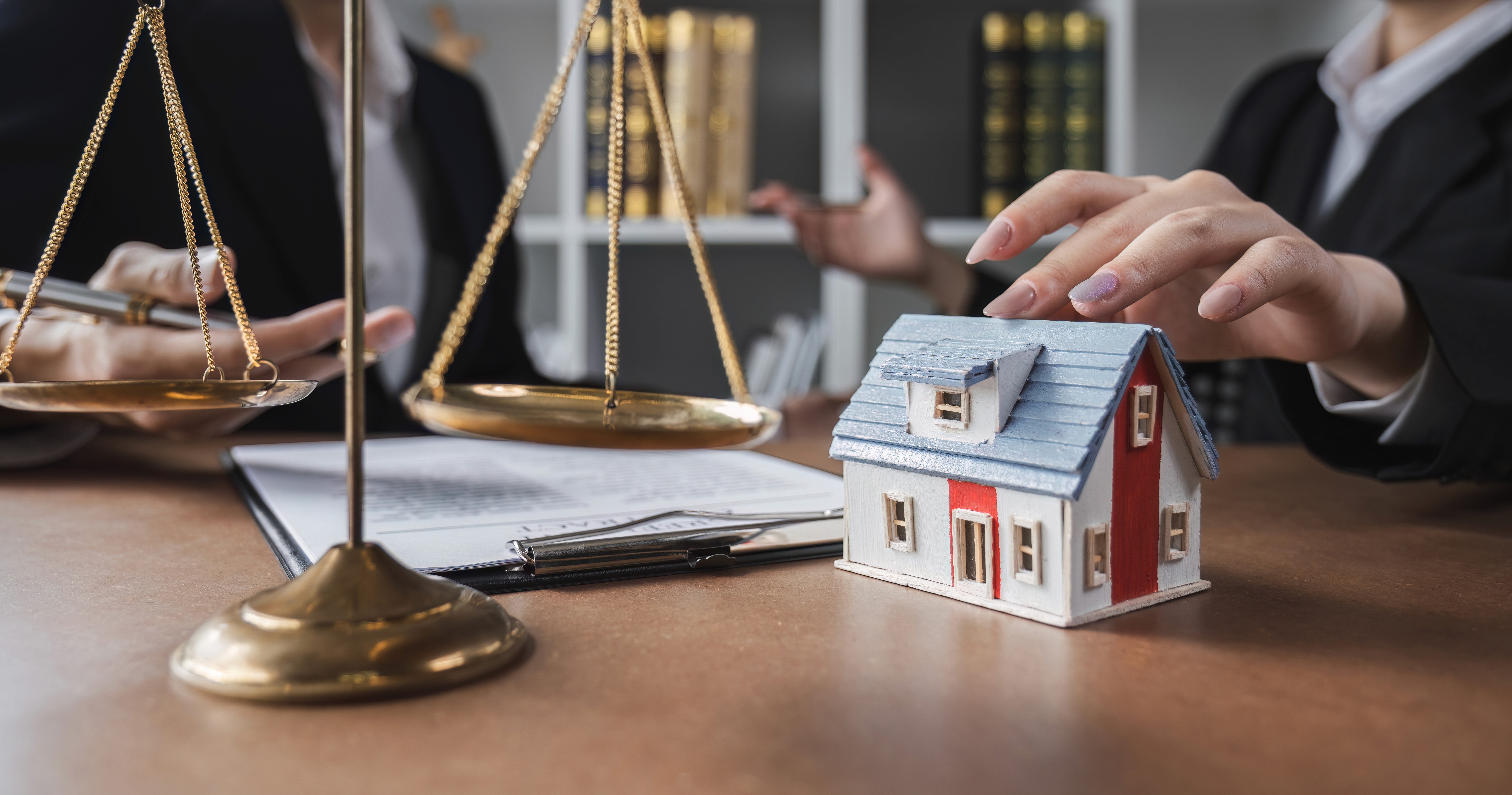 Attorney reviewing estate planning documents with scales of justice and a model home on the desk, representing wills, trusts, and probate services in Essex County, MA