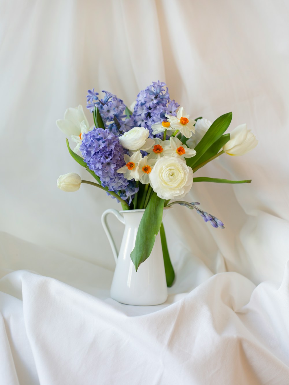 Purple hyacinths and white narcissi in a white jug