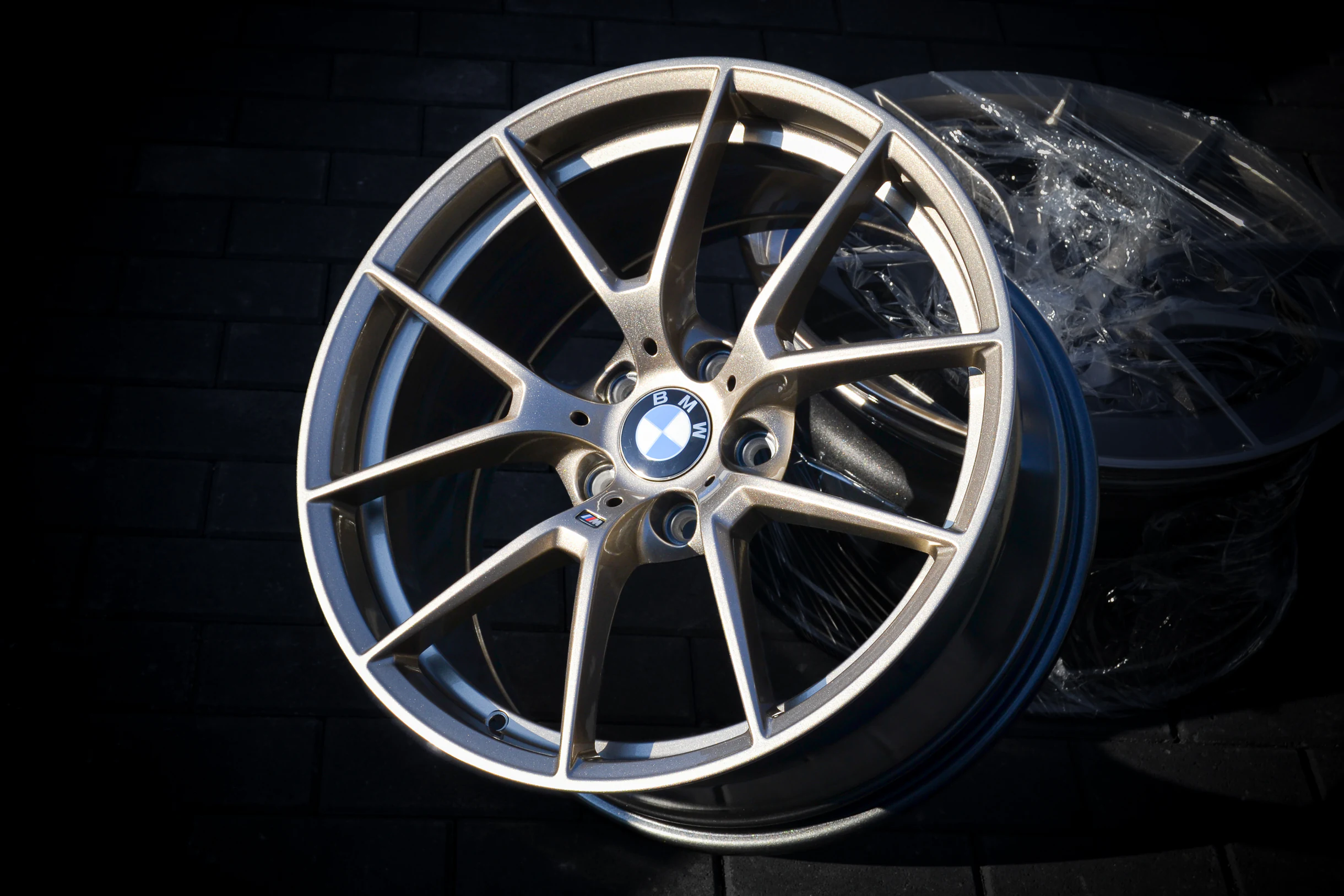 Zweifarbige BMW-Felge mit hellen Speichenfronten und dunklen Vertiefungen bei AT Plus.