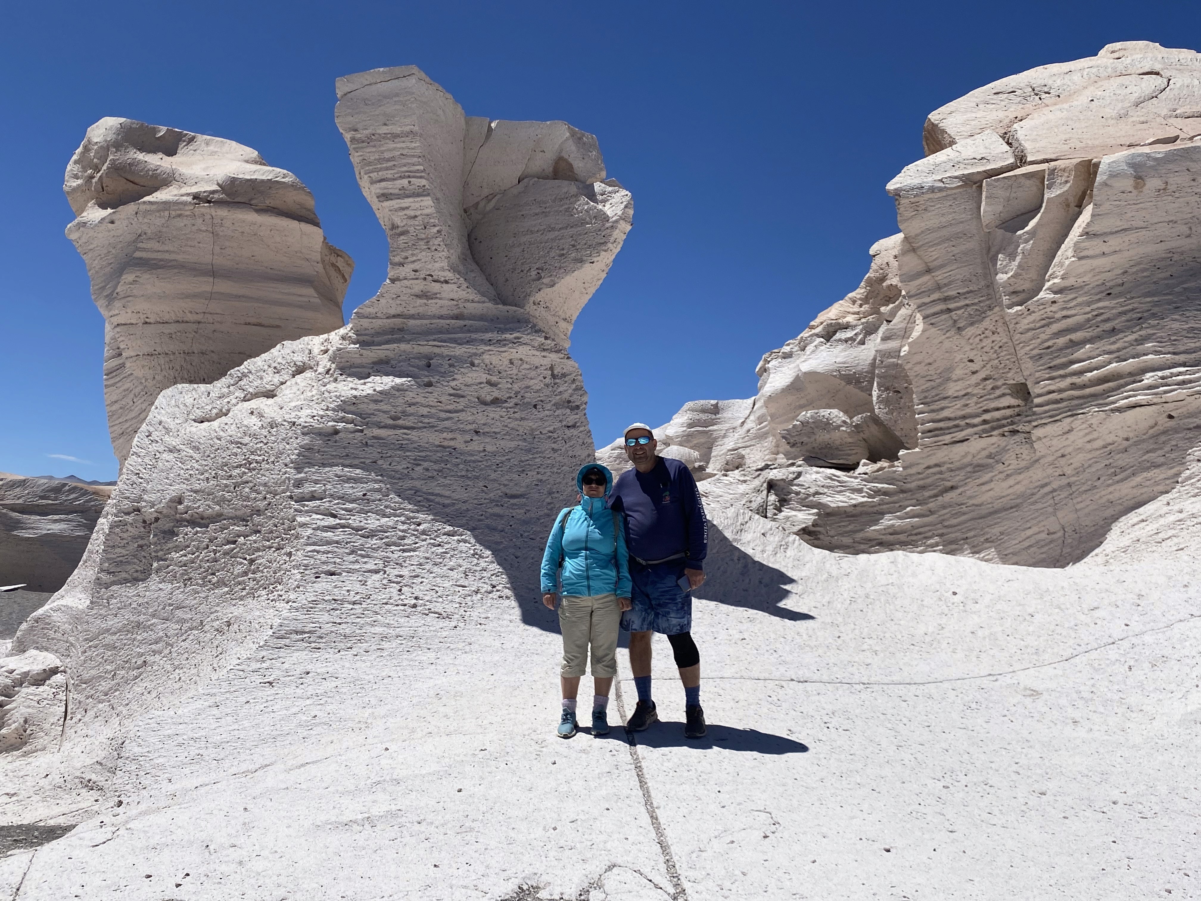 Mujer sentada sobre un tronco frente a una cascada doble en un bosque frondoso de Argentina.