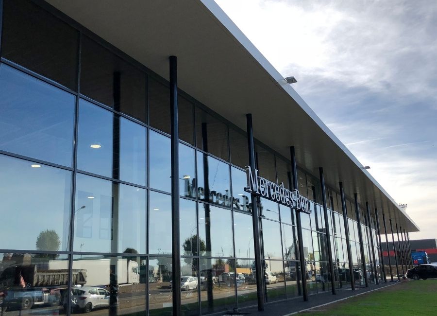 Façade vitrée moderne d’un bâtiment industriel avec auvent métallique en saillie.