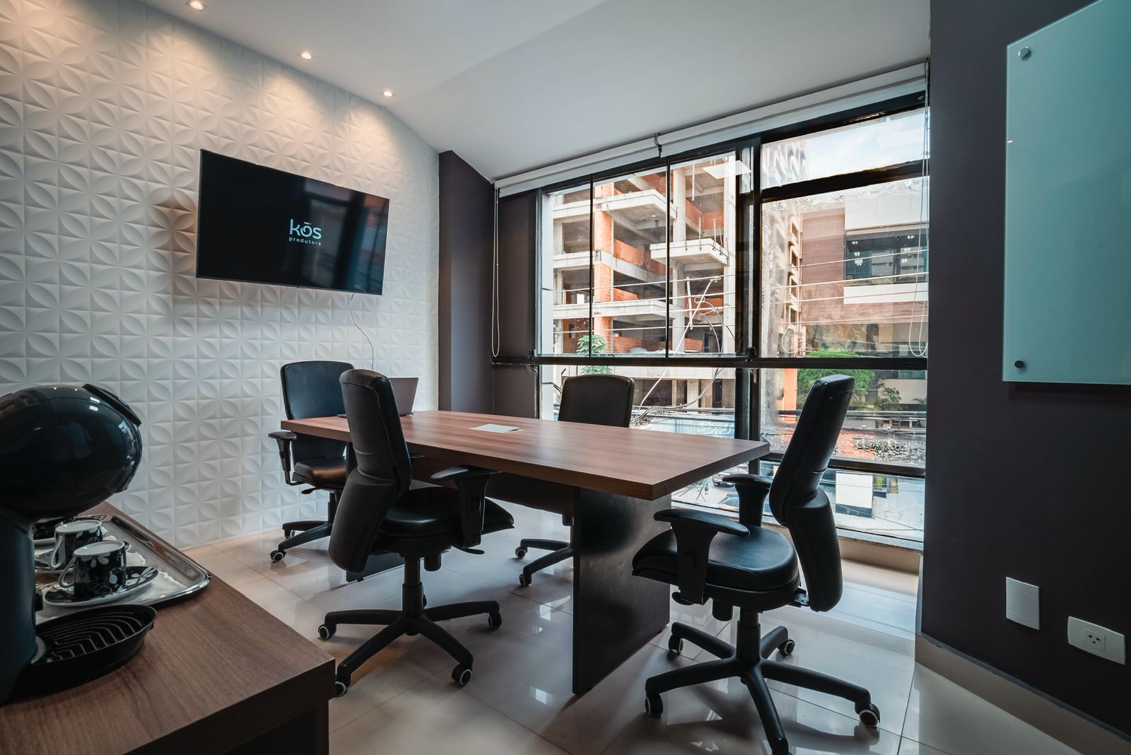 Modern red brick apartment or office building viewed from below against a blue sky, showcasing its geometric architecture with evenly spaced windows and balconies.