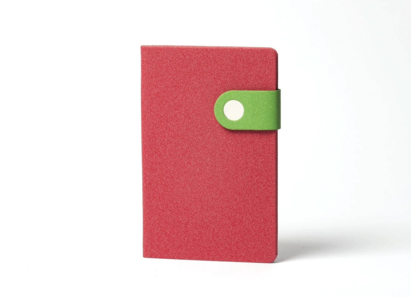 Front view of standing red notebook with green button strap.