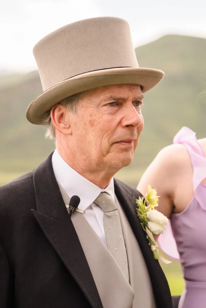 A portrait of a man in a formal black morning suit and a grey top hat attending a Chaparral Ranch Wedding.