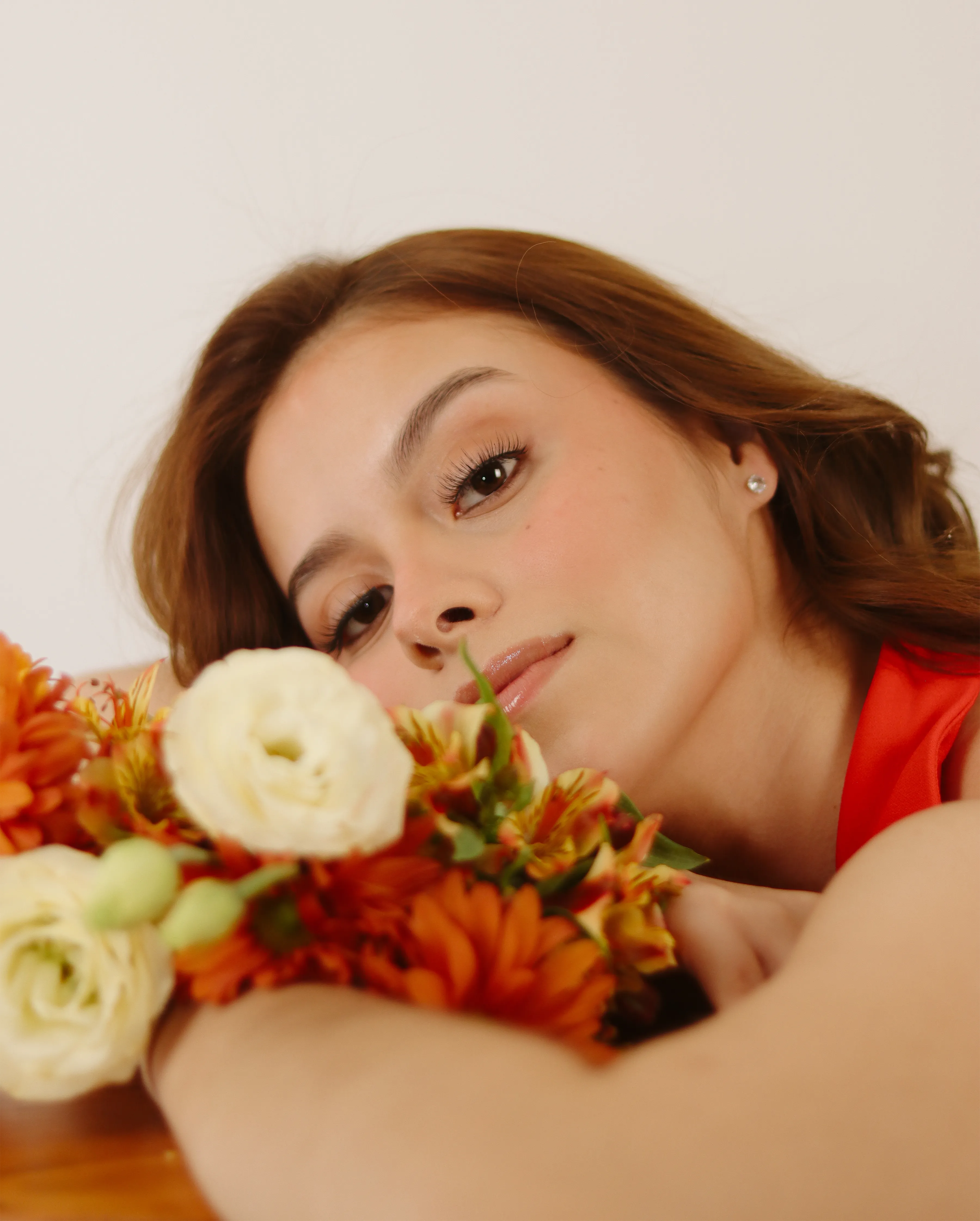 Retrato de mujer recostada entre flores mirando al frente
