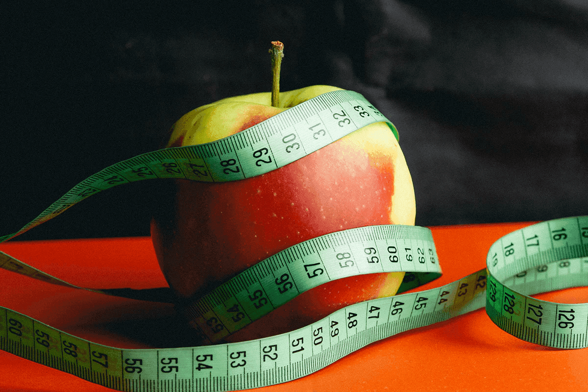 Apple with measuring tape representing nutrition, weight management, and muscle health