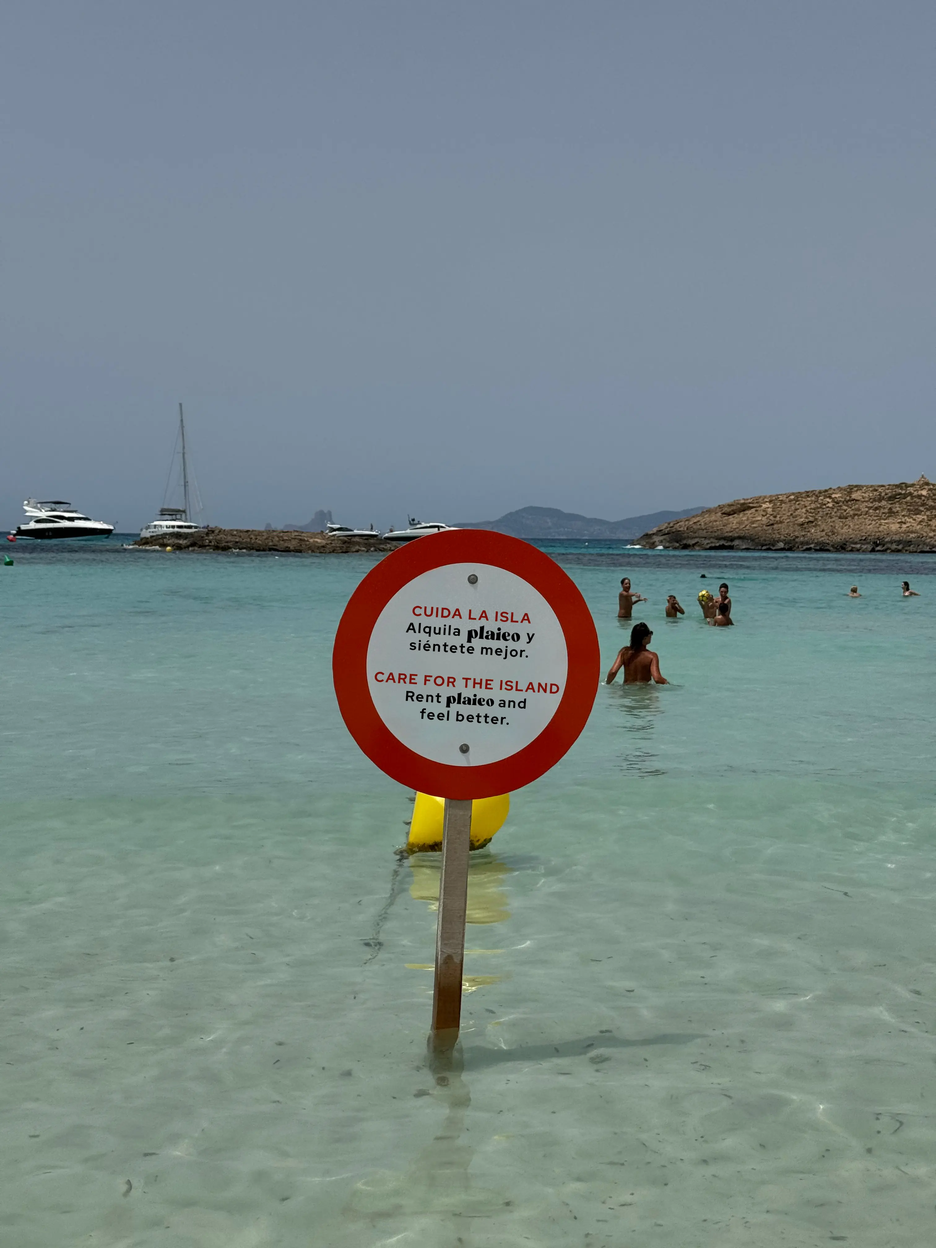 Señal de trafico clavaada en la orilla del mar con texto sobre plaieo