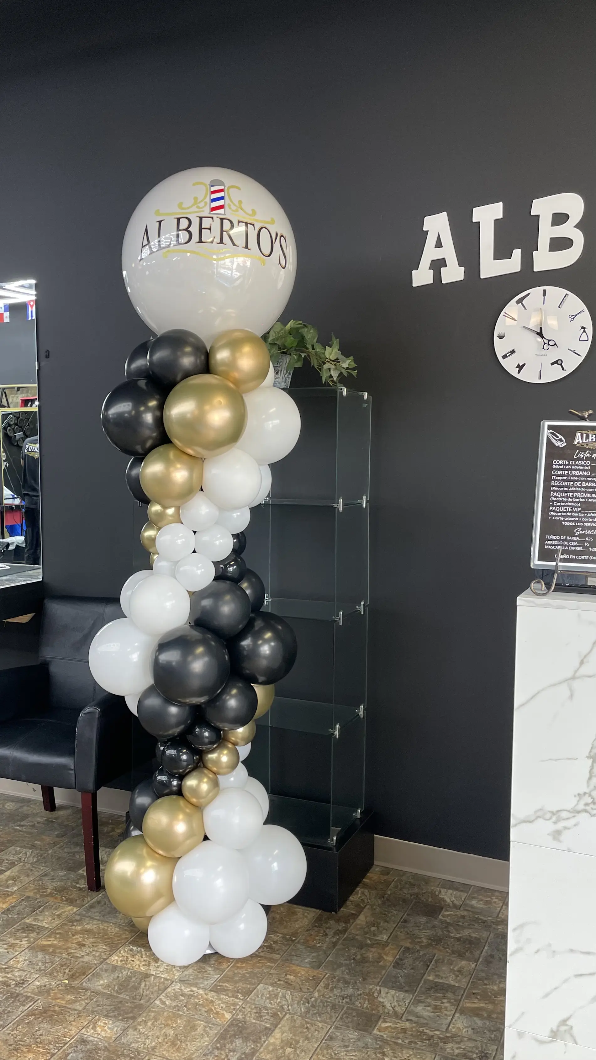 Elegant balloon column in a sophisticated black, white, and gold color scheme, arranged in an organic style with a mix of sizes for a classy and modern look. Ideal for upscale events or formal celebrations. Susa’s Sweets & Balloons.