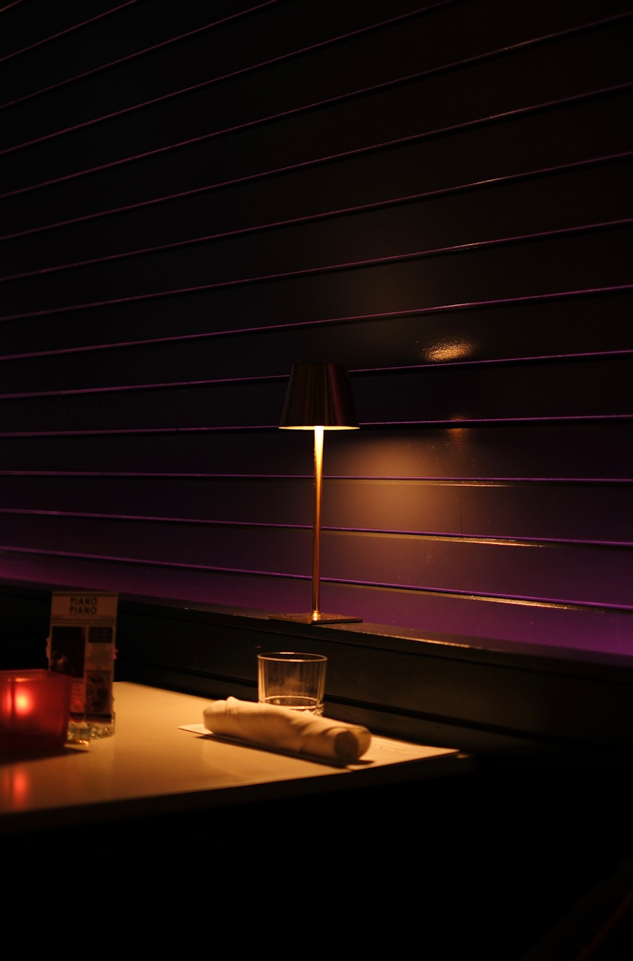 A dimly lit table with a lamp and drink