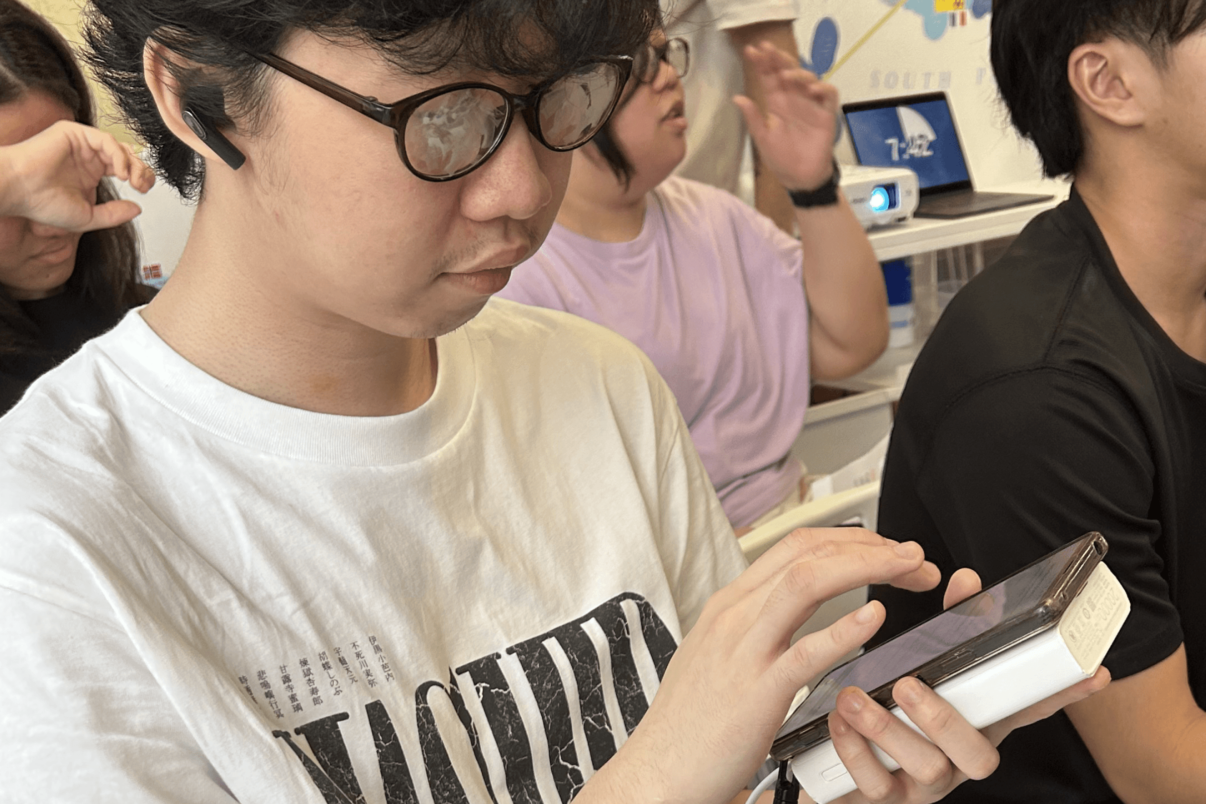 A participant from our workshop trying out screen reader function on his phone, while wearing our DIY glasses with blurry lenses.
