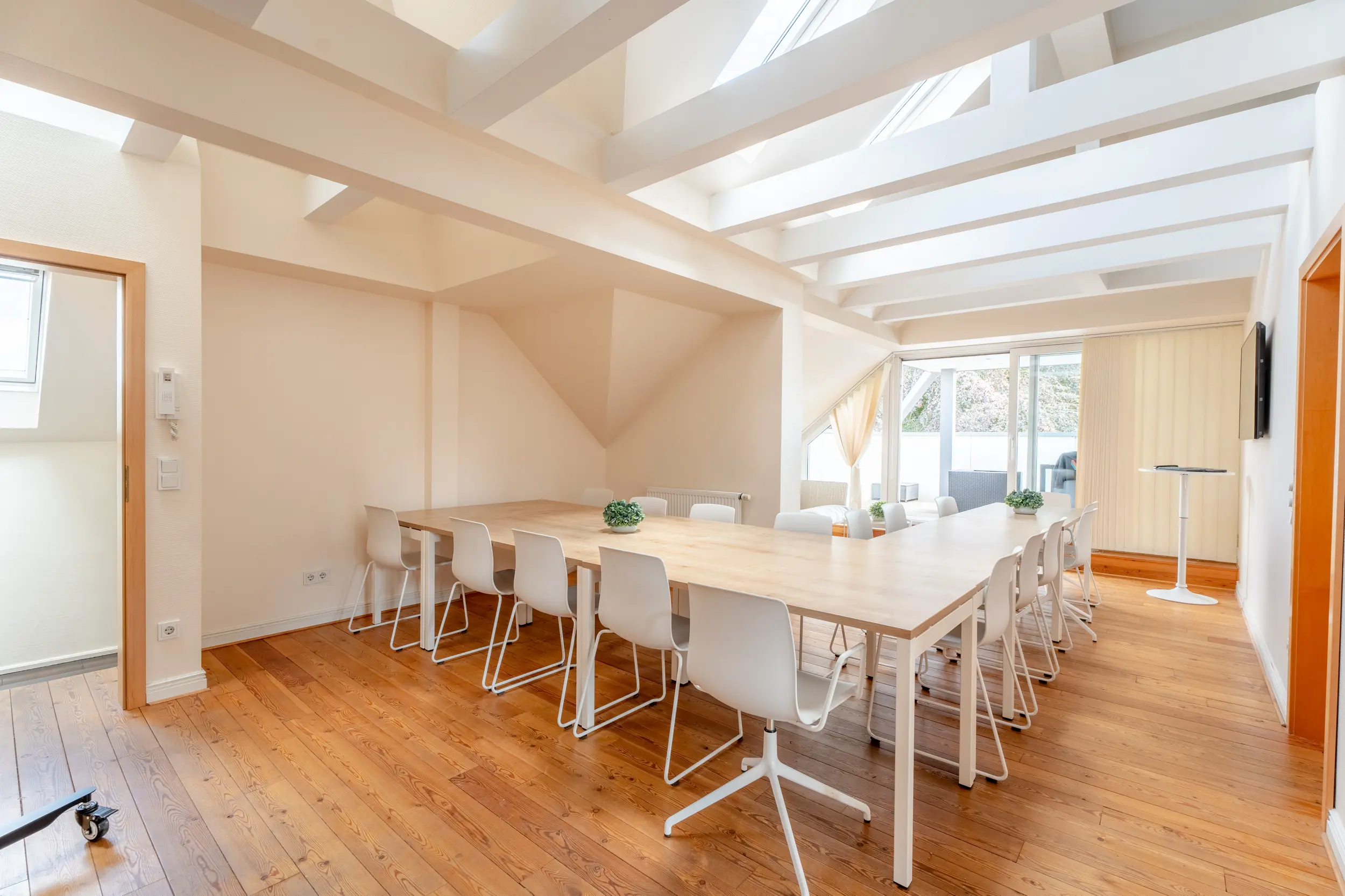 Konferenzraum im Dachgeschoss der Bürovilla Gronau (Westfalen) mit langem Tisch und Zugang zur Dachterrasse