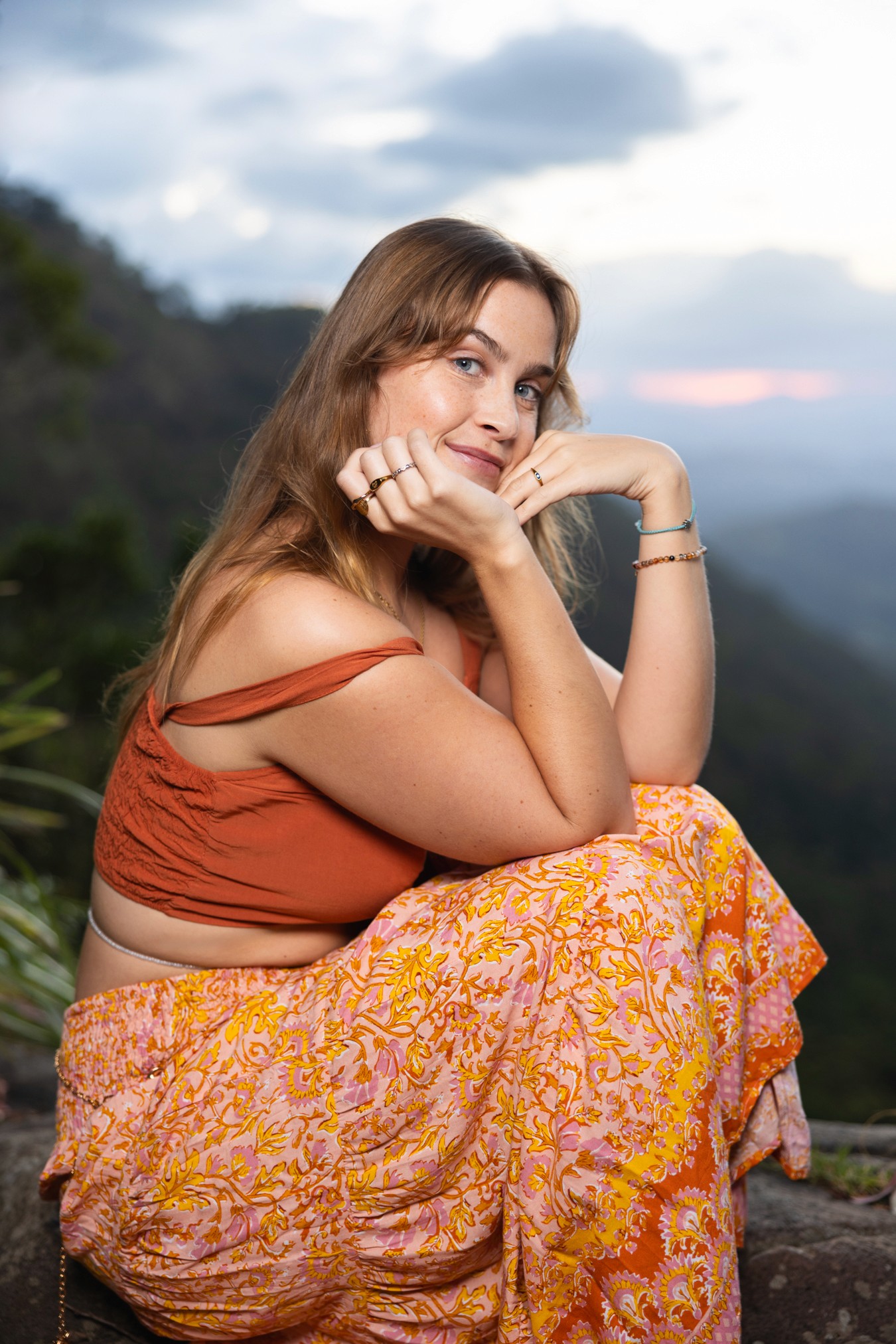 Young woman sitting in front of mountain range at sunet