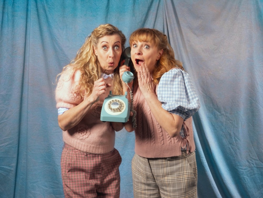 Two people holding balloons and touching heads on the cheek.