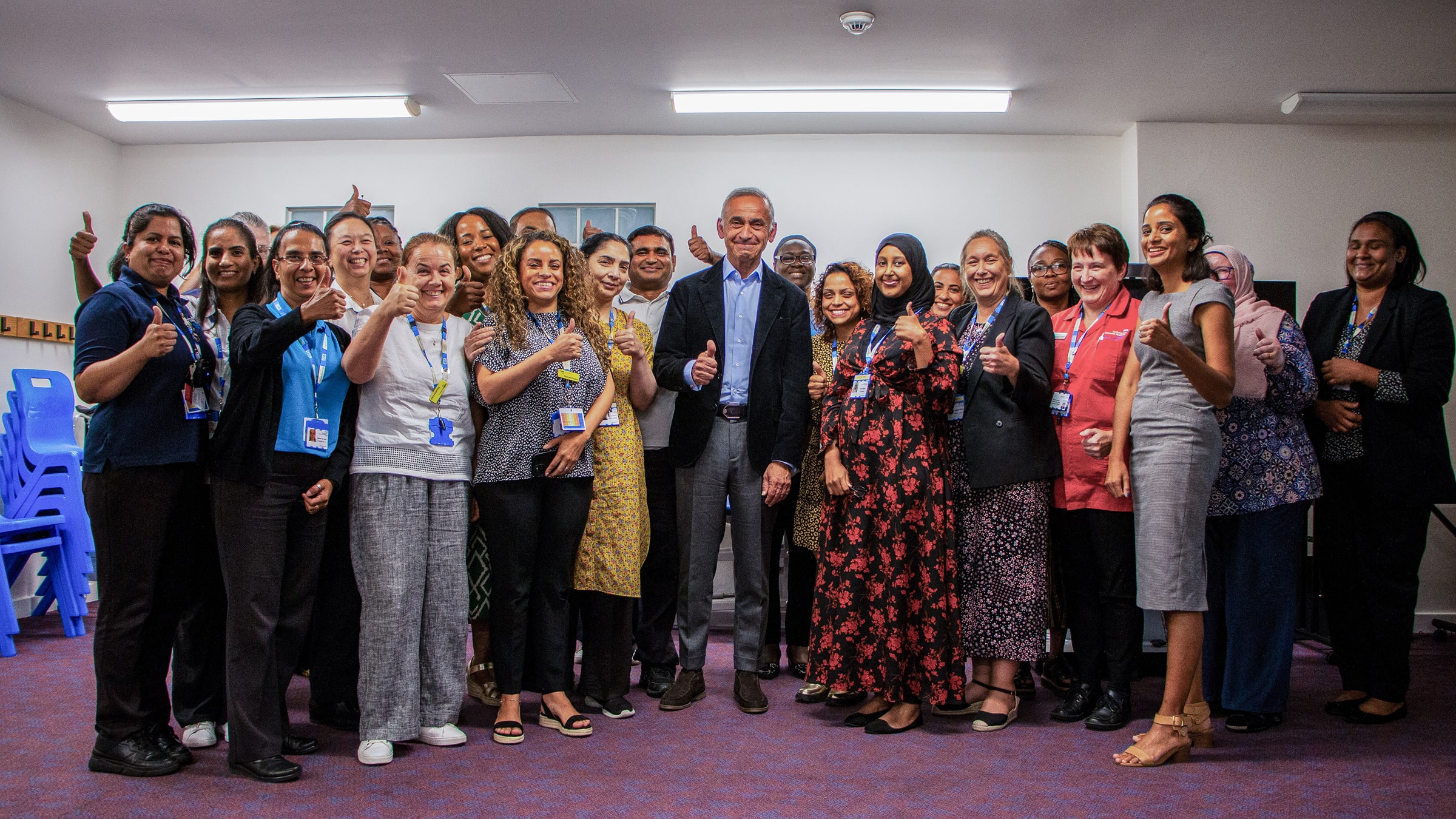 Group photograph of NHS workers gathered around Lord Darzi, all doing a thumbs up to the camera