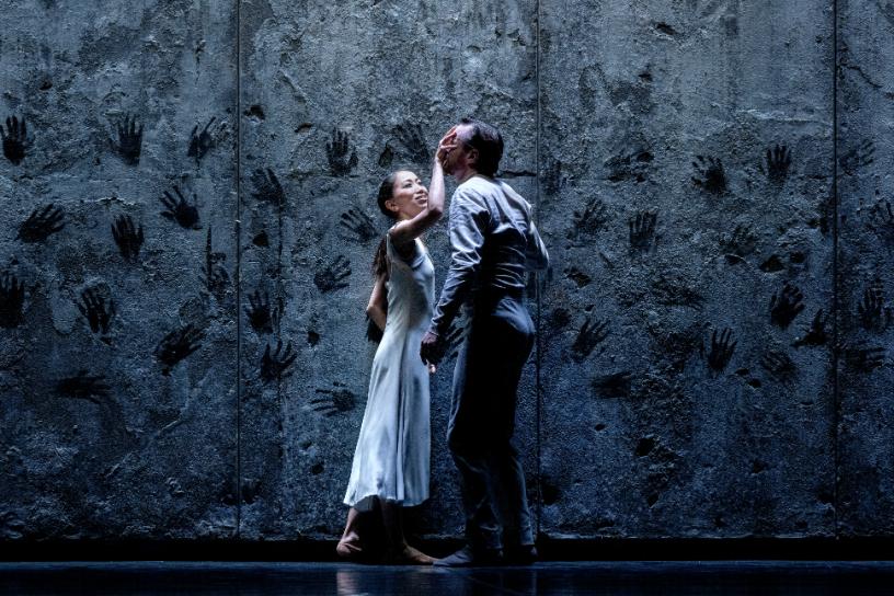 Two dancers sharing an emotional moment before a wall of handprints in Akram Khans Giselle.